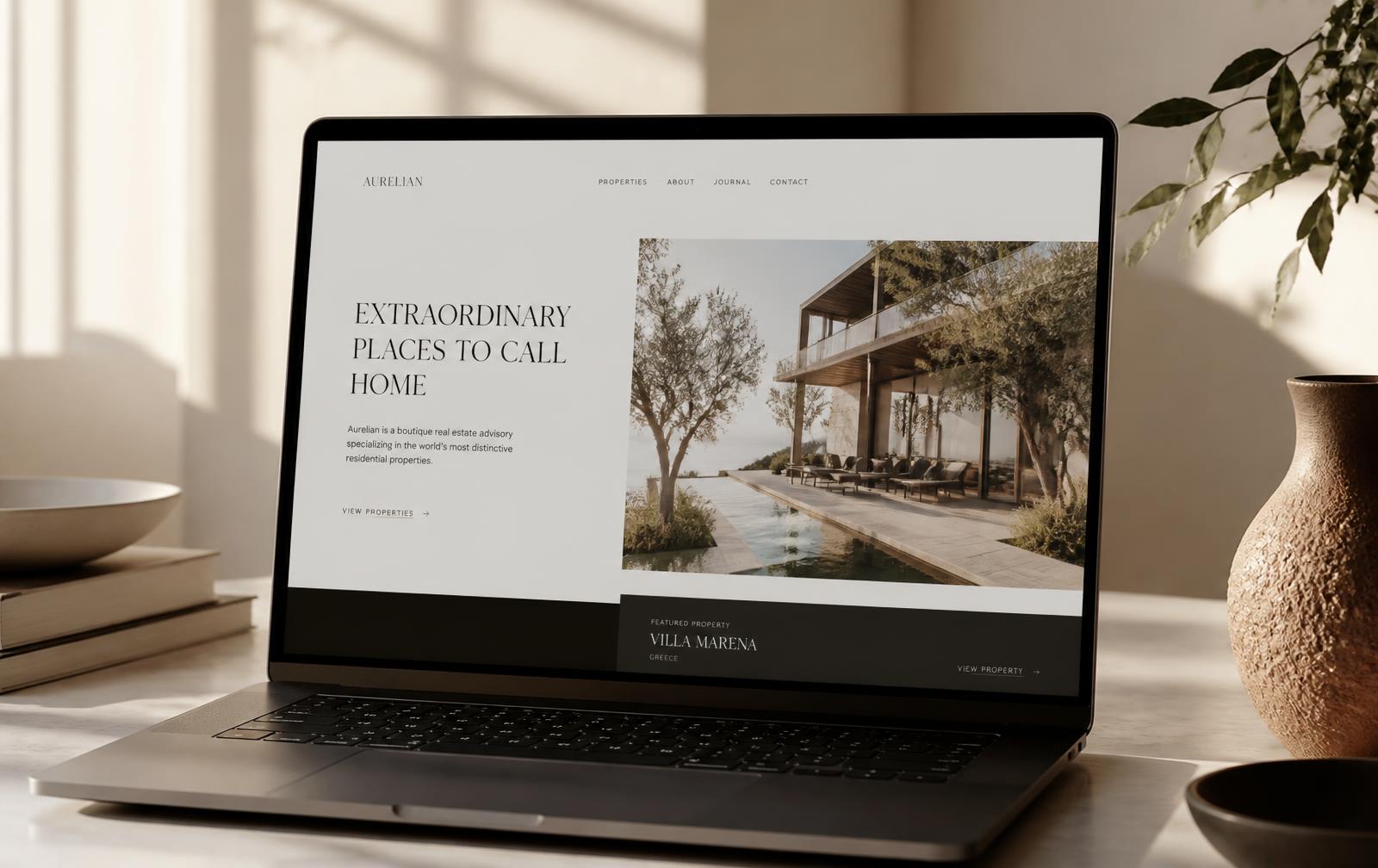 Laptop on a warm desk showing a refined, minimal real estate website with serif headlines and architectural photography.